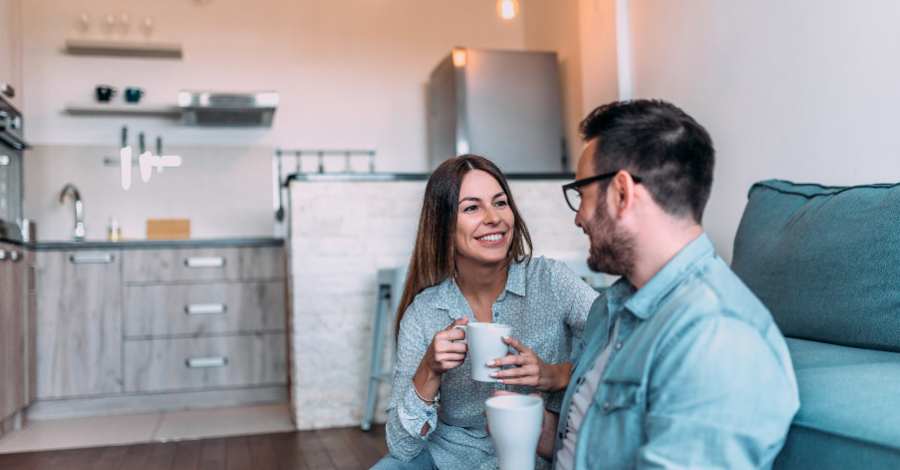 Casal sorrindo enquanto toma café da manhã em casa